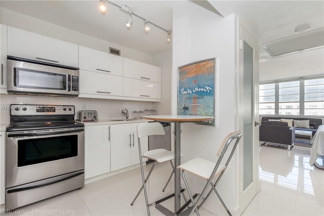 100 Lincoln Road, Unit 806 Miami Beach, FL 33139 - Photo 7 of 23 a kitchen with stainless steel appliances kitchen island granite countertop a stove top oven microwave and furniture