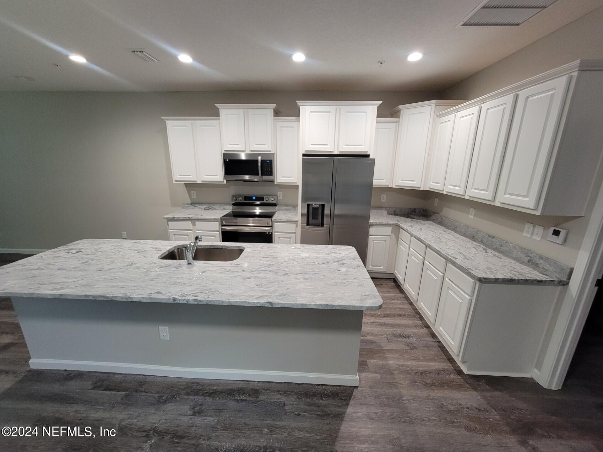 4146 Quiet Creek Loop, Unit 131 Middleburg, FL 32068 - Photo 6 of 39 a large kitchen with stainless steel appliances kitchen island granite countertop a sink a stove and a refrigerator