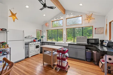 a kitchen with stainless steel appliances granite countertop a stove top oven a refrigerator a dining table and chairs with wooden floor