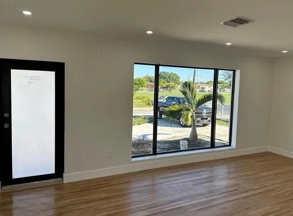 an empty room with wooden floor and windows with curtains