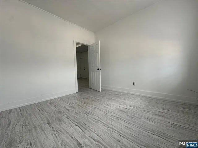 a view of an empty room with wooden floor and closet