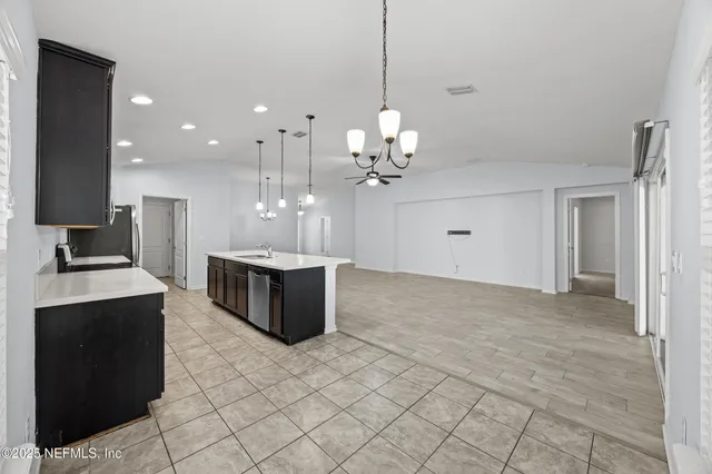 a large kitchen with kitchen island a sink stainless steel appliances and a chandelier