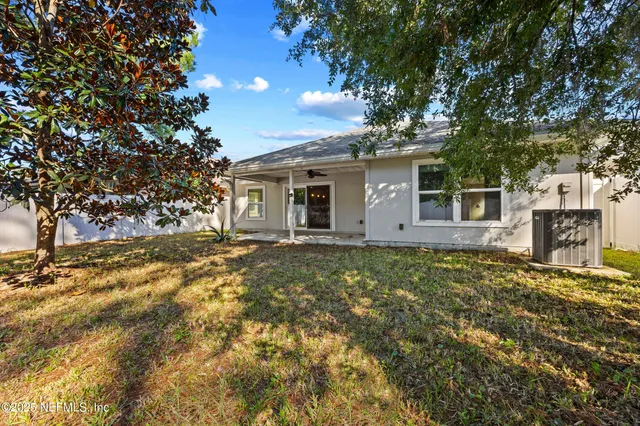 a backyard of a house with large trees and table and chairs