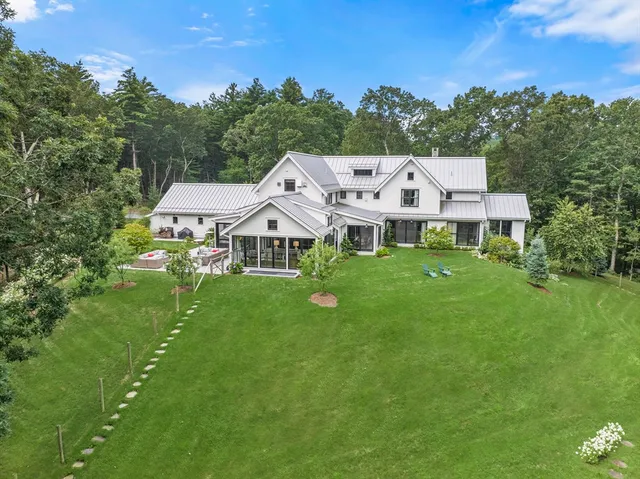 a view of a white house with a big yard plants and large trees