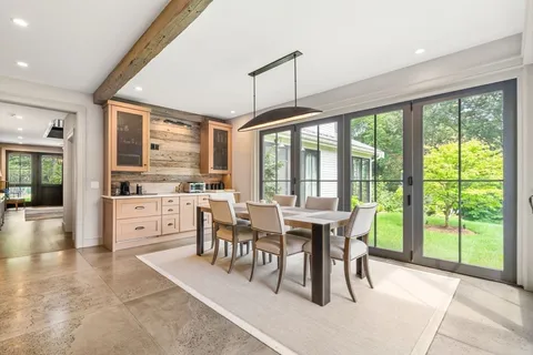 a view of a dining room and livingroom with furniture large windows a chandelier