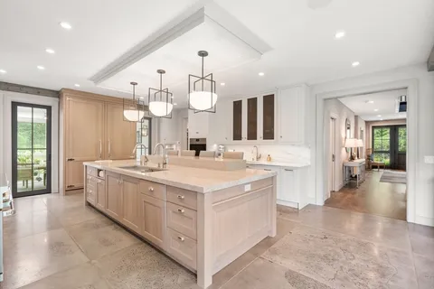 a large white kitchen with a large island oven a stove and white cabinets