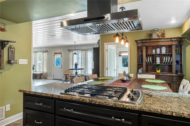 a kitchen with kitchen island granite countertop a stove and a sink