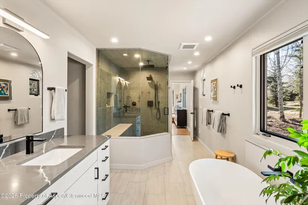 a large bathroom with a granite countertop tub sink a mirror a shower and vanity