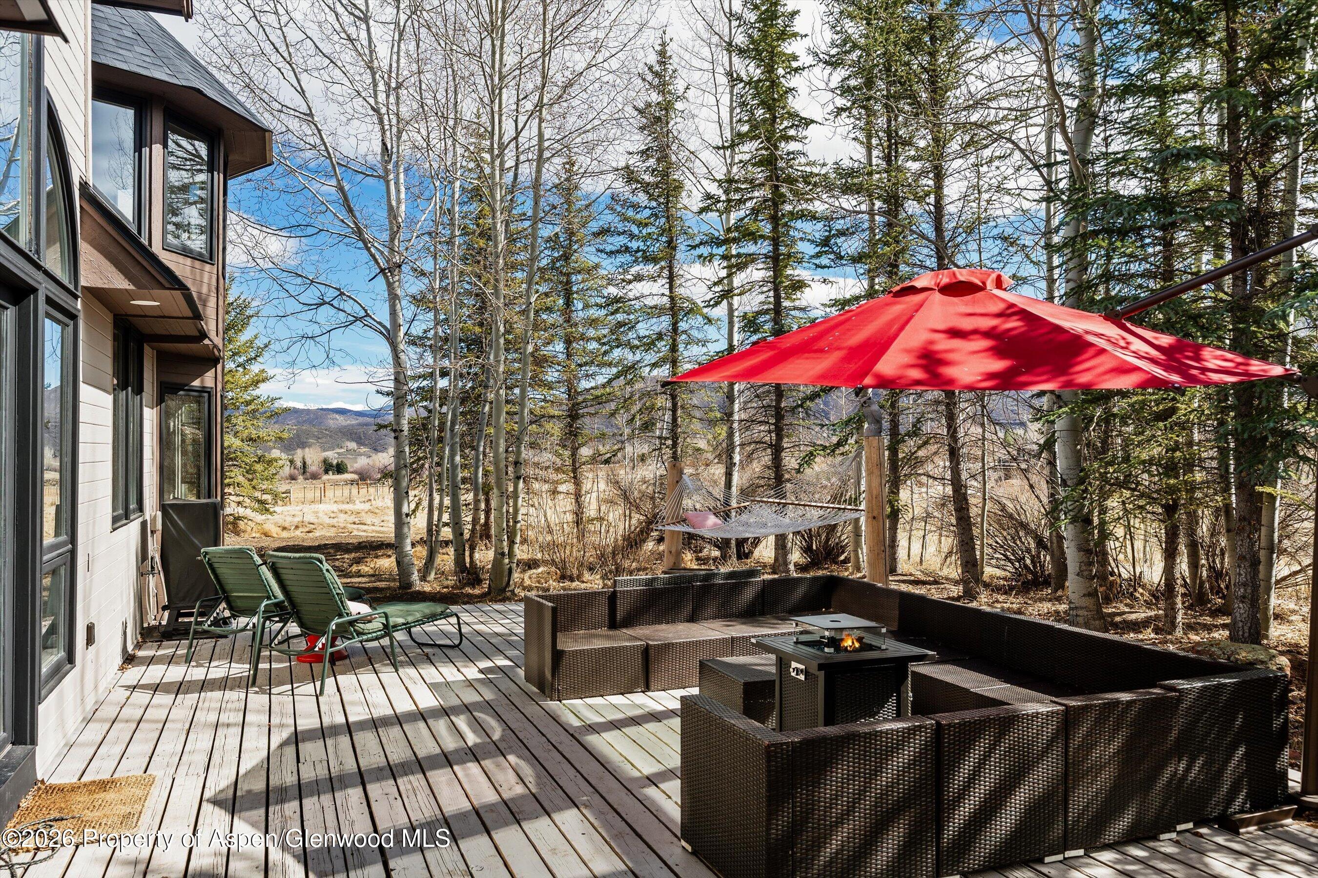90 Alexander Avenue Snowmass, CO 81654 - Photo 24 of 26 a view of a patio with a table and chairs under an umbrella with barbeque grill and wooden floor