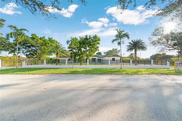 a view of a house with a yard and palm trees