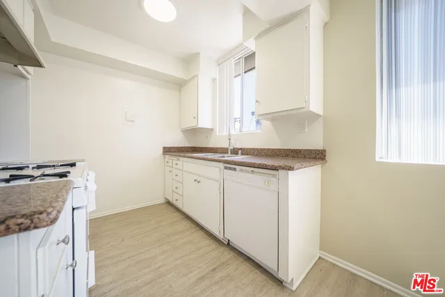 a kitchen with granite countertop a sink stove and cabinets