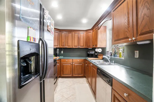 a kitchen with stainless steel appliances granite countertop a sink refrigerator and cabinets