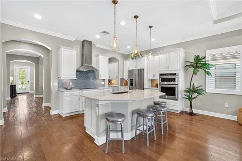 a large kitchen with kitchen island white cabinets and stainless steel appliances