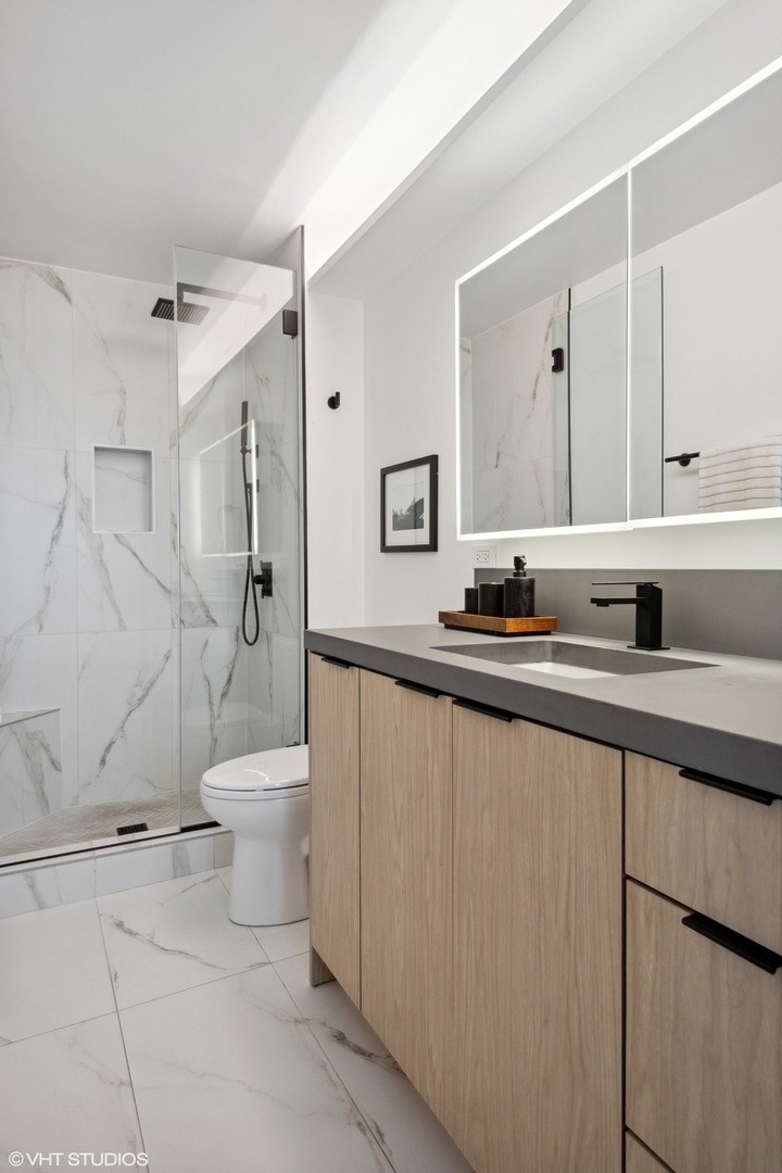 1030 North State Street, Unit 21E Chicago, IL 60610 - Photo 21 of 42 a bathroom with a sink a toilet and a mirror
