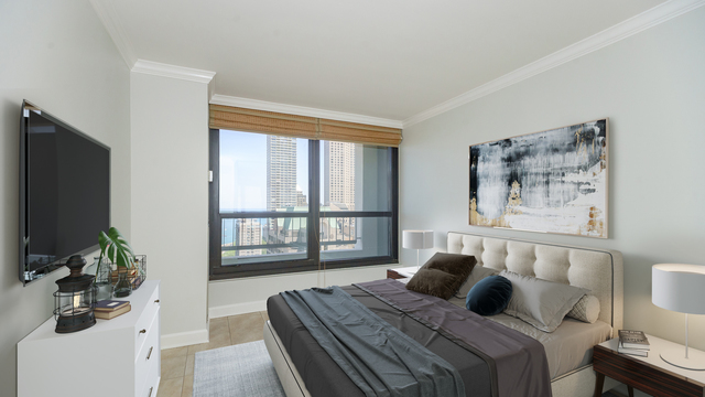1030 North State Street, Unit 21E Chicago, IL 60610 - Photo 23 of 42 a bedroom with a large bed and a flat tv screen on a dresser