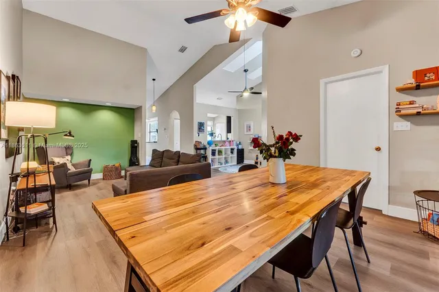 a dining room with wooden floor a chandelier a wooden table and chairs