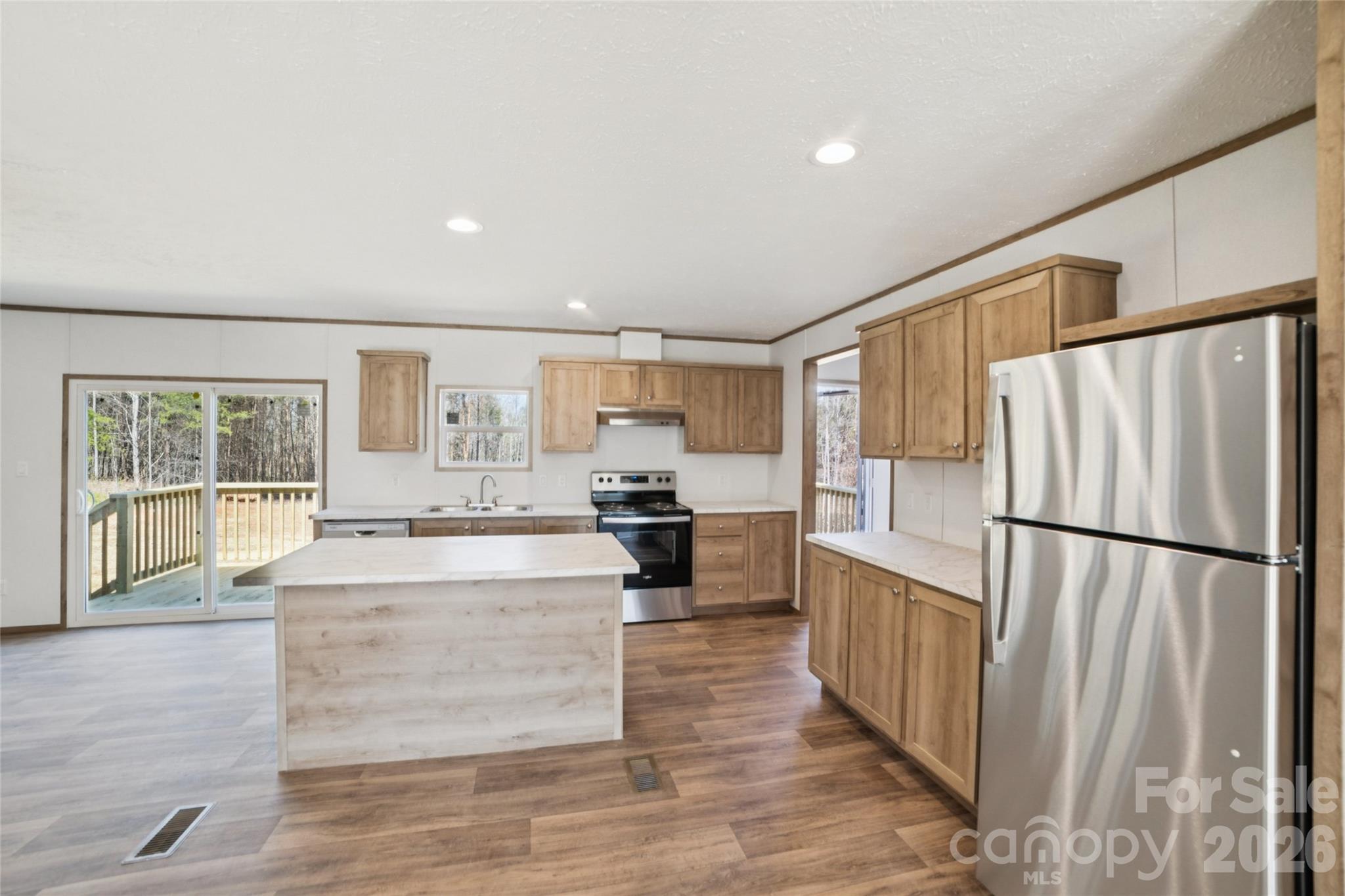 5350 Hope Road Vale, NC 28168 - Photo 6 of 24 a large white kitchen with kitchen island a refrigerator a stove a sink dishwasher a oven with white cabinets and wooden floor