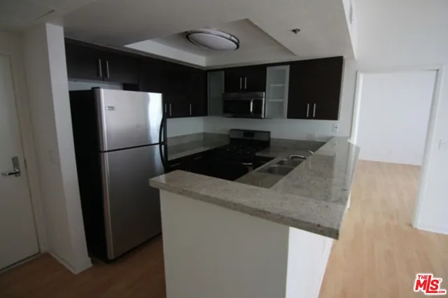 a kitchen with stainless steel appliances granite countertop a refrigerator a stove and a sink