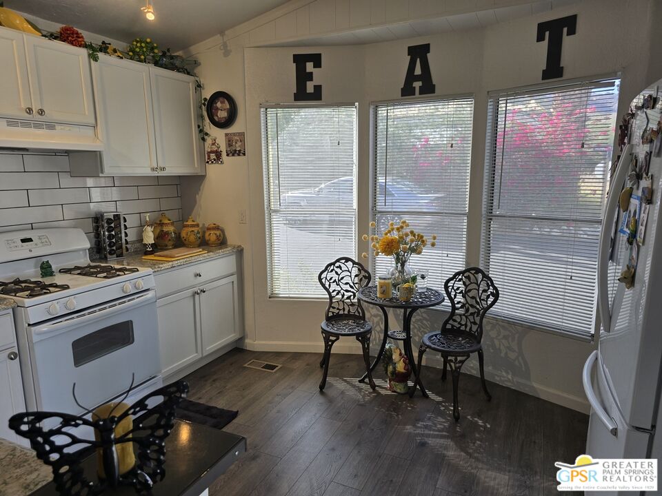 1 Running H Palm Desert, CA 92260 - Photo 7 of 22 a kitchen with stainless steel appliances granite countertop a stove a refrigerator a dining table and chairs with wooden floor
