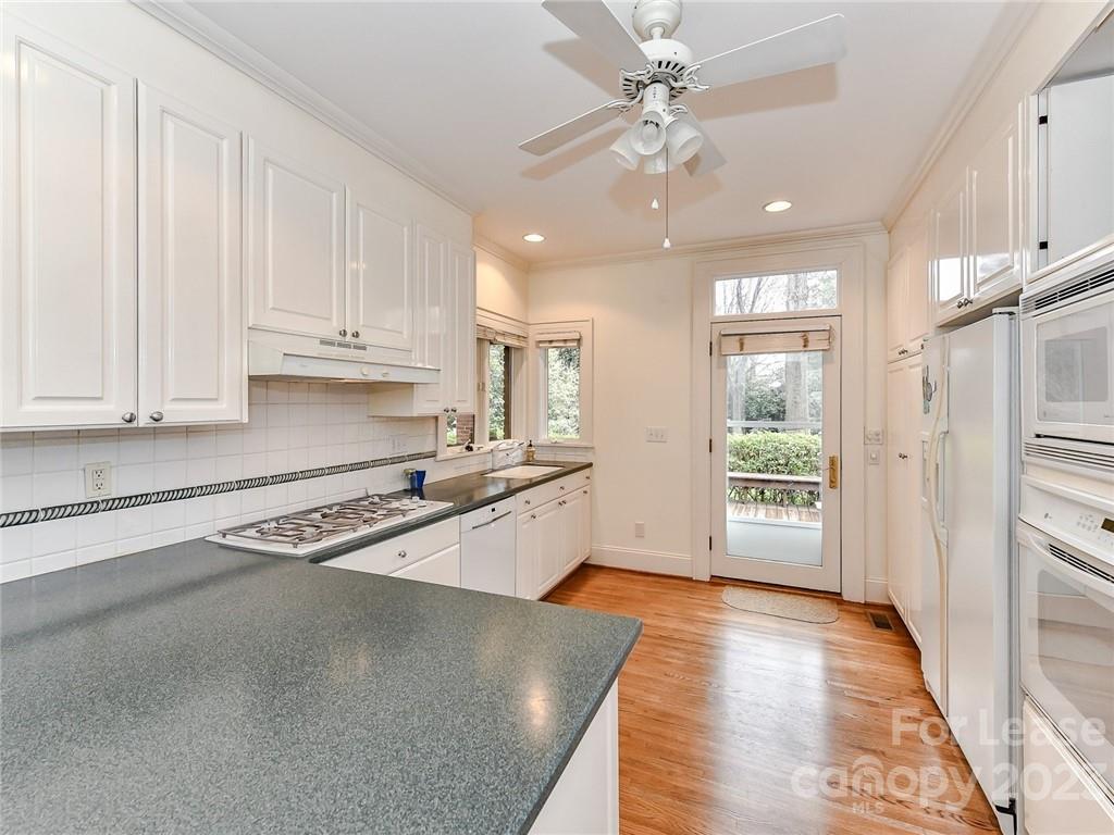 1923 Ewing Avenue Charlotte, NC 28203 - Photo 11 of 39 a kitchen with stainless steel appliances granite countertop a stove a sink and white cabinets with wooden floor