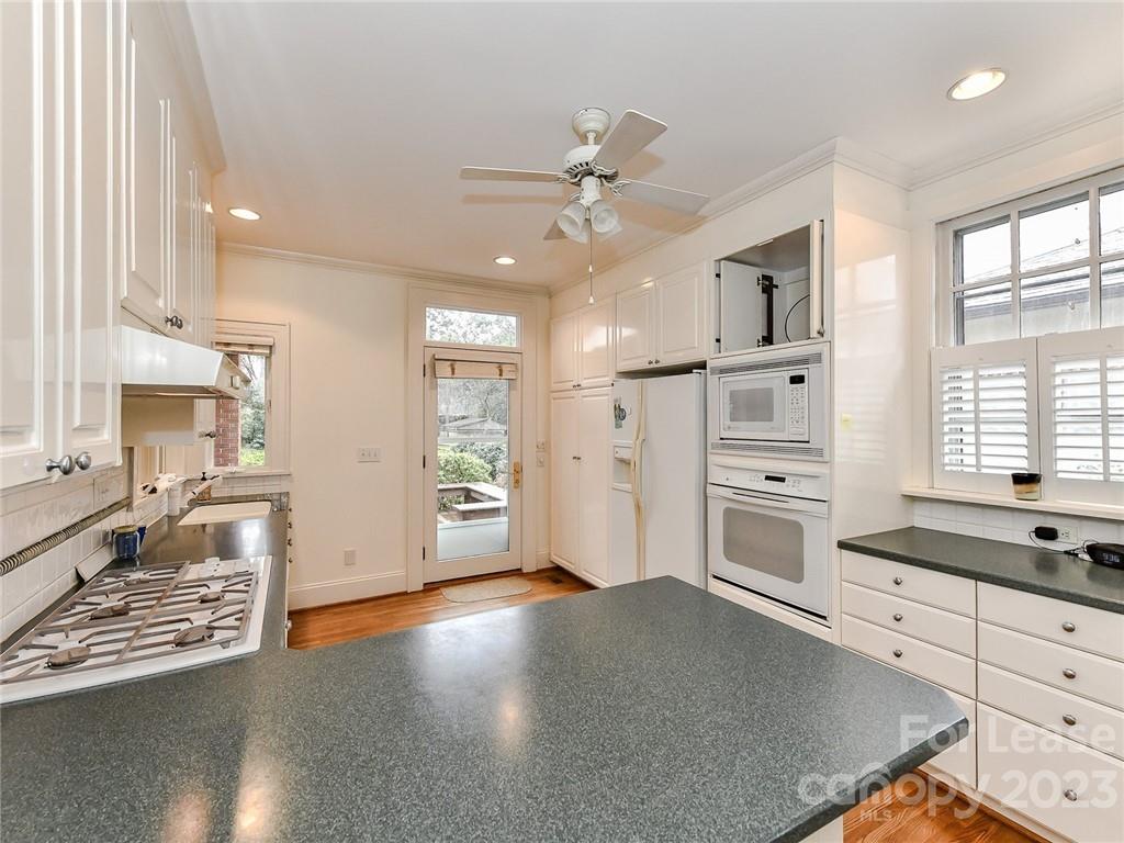 1923 Ewing Avenue Charlotte, NC 28203 - Photo 12 of 39 a living room with stainless steel appliances kitchen island granite countertop a stove a refrigerator a sink a dining table and chairs with wooden floor