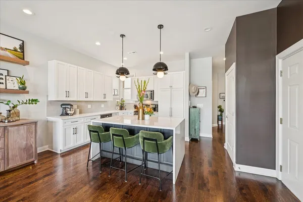 a kitchen with stainless steel appliances a dining table chairs stove and white cabinets