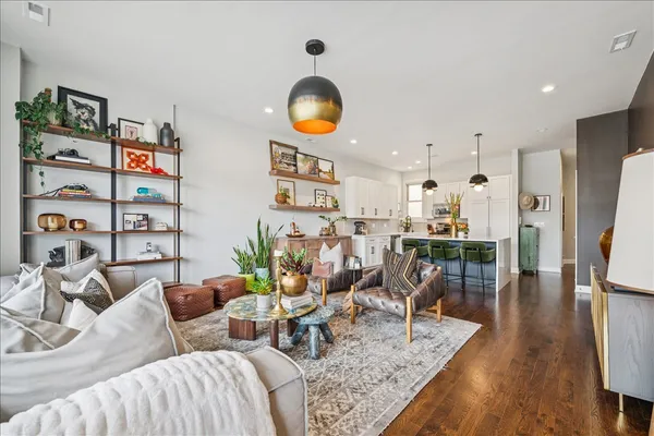 a living room with furniture kitchen view and wood floor