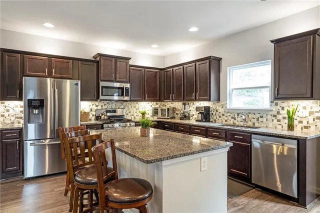 a kitchen with a sink a kitchen island stainless steel appliances cabinets and a window