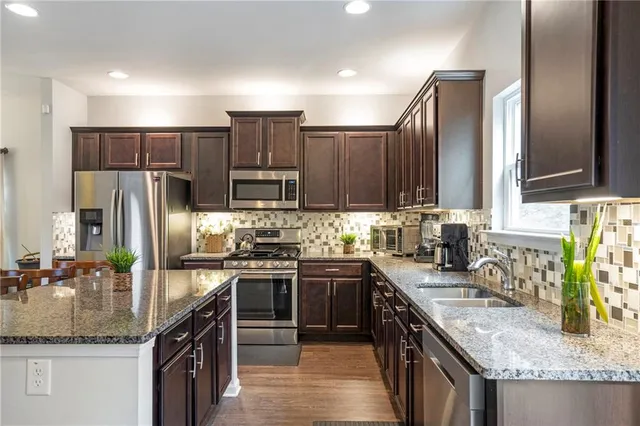 a kitchen with stainless steel appliances granite countertop a sink stove refrigerator and cabinets