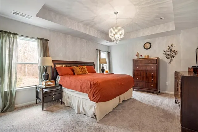 a spacious bedroom with a bed and a chandelier