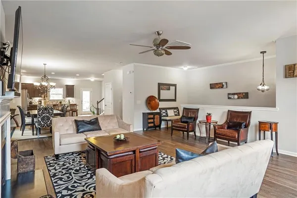 a living room with furniture kitchen view and a chandelier