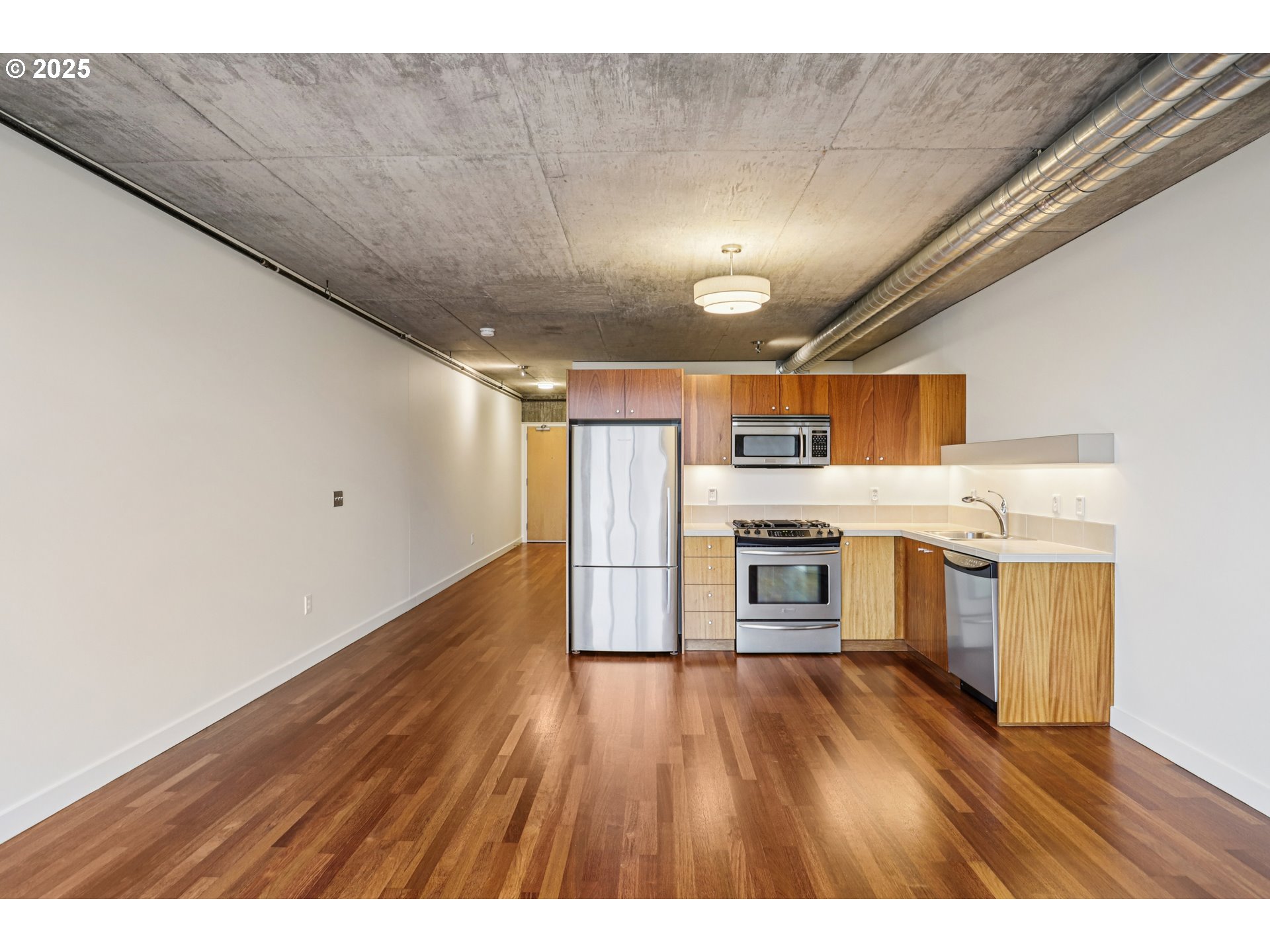 1926 West Burnside Street, Unit 906 Portland, OR 97209 - Photo 12 of 26 a open kitchen with a wooden floor stove top oven and refrigerator