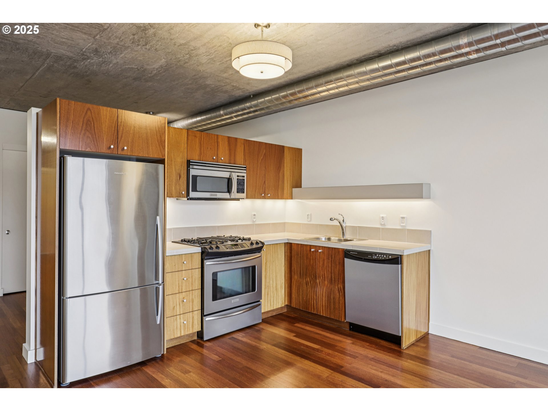 1926 West Burnside Street, Unit 906 Portland, OR 97209 - Photo 13 of 26 a kitchen with stainless steel appliances granite countertop a refrigerator a stove a sink and a microwave