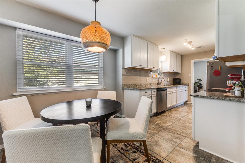 5131 Menefee Drive Dallas, TX 75227 - Photo 12 of 22 a kitchen with kitchen island granite countertop a sink cabinets a dining table and chairs