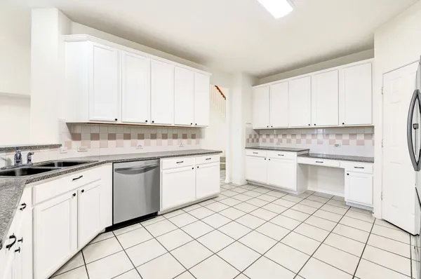 a kitchen with granite countertop white cabinets stainless steel appliances a sink and a window