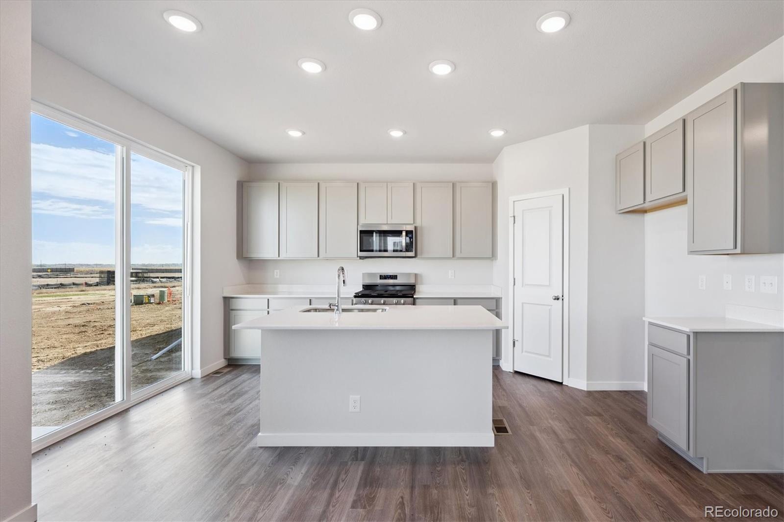 14434 Ranch Street Mead, CO 80504 - Photo 4 of 27 a kitchen with stainless steel appliances granite countertop a stove top oven a refrigerator a sink and white cabinets with wooden floor