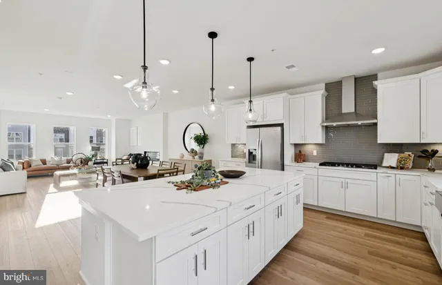 a kitchen with stainless steel appliances kitchen island granite countertop a stove a sink a dining table and chairs with wooden floor