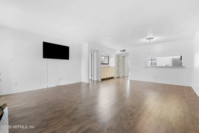 a view of a livingroom with wooden floor and a flat screen tv