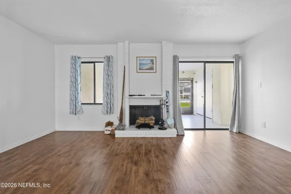 a view of an empty room with fire place and windows