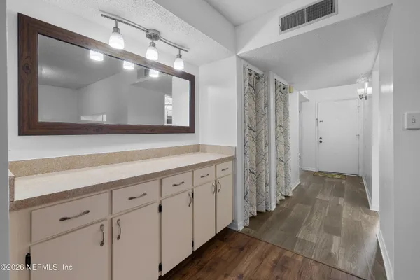 a view of a hallway with wooden floor and cabinet