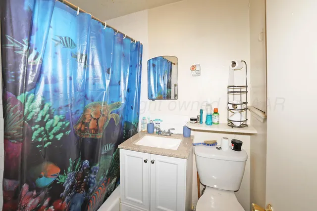 a bathroom with a toilet a sink and curtain