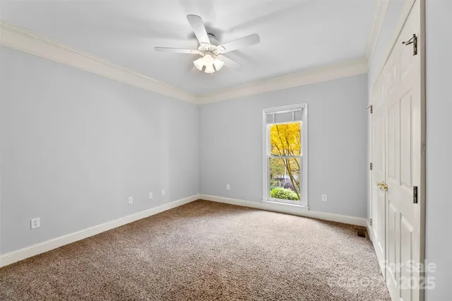 a view of an empty room with chandelier fan