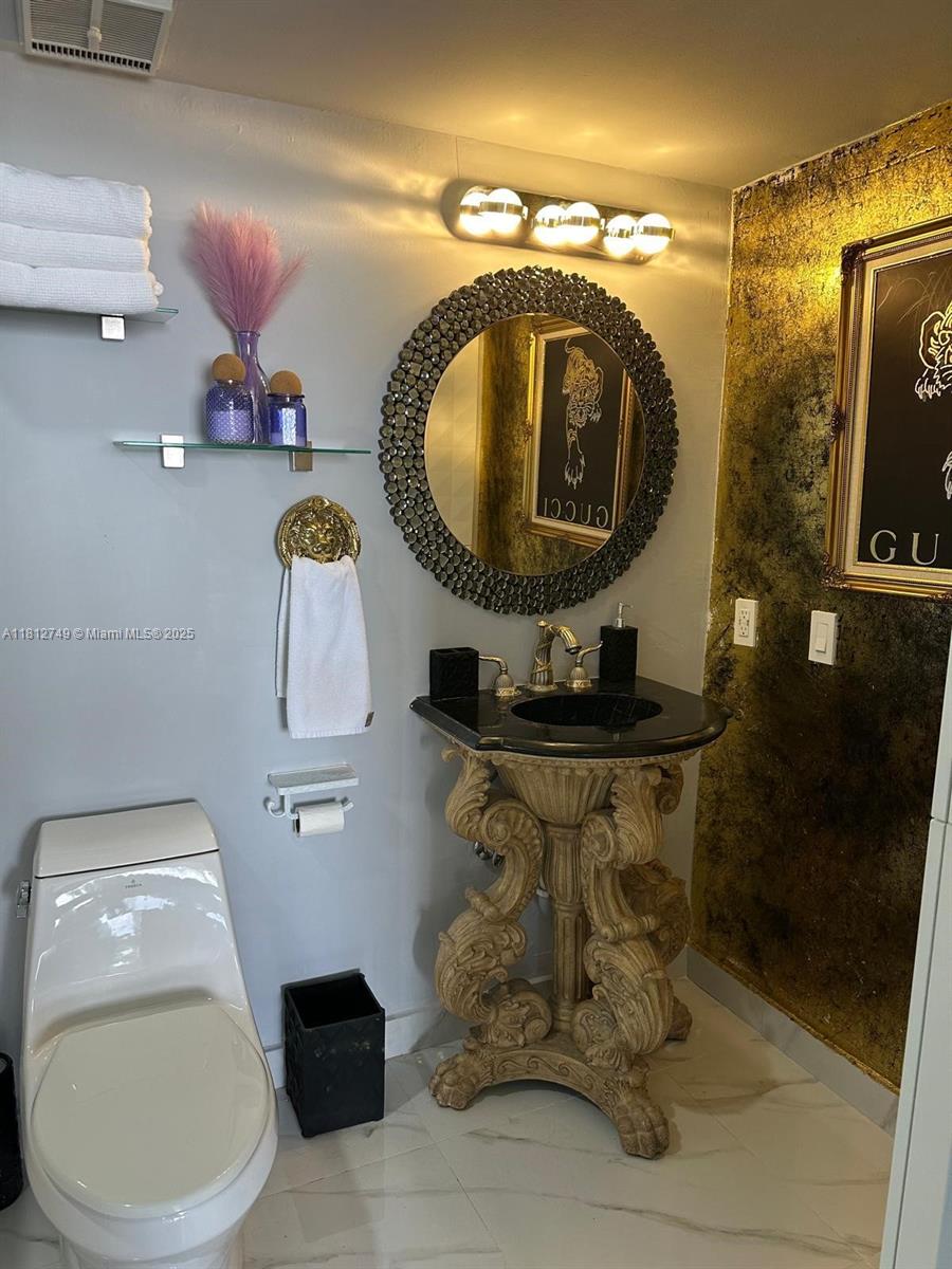 7601 East Treasure Drive, Unit 2022 North Bay Village, FL 33141 - Photo 12 of 16 a bathroom with a toilet a sink and mirror