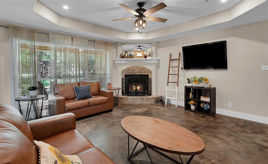 37 Bluebonnet Loop Morgan's Point Resort, TX 76513 - Photo 6 of 38 Living area featuring a brick-surround fireplace with a hearth, a mounted television, a ceiling fan with integrated lighting, recessed lighting, and a tray ceiling
