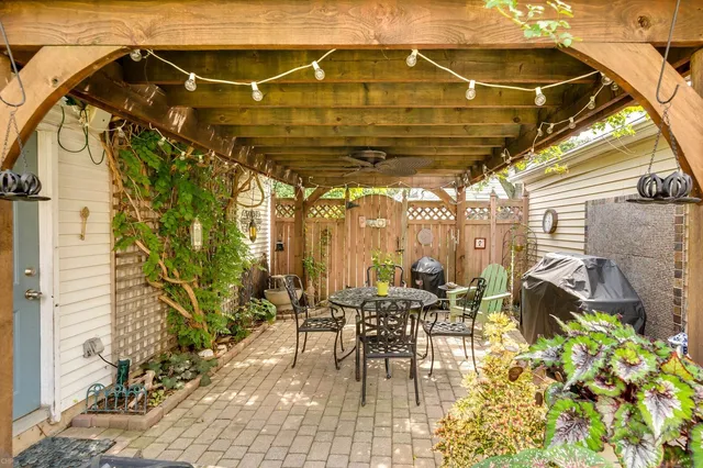 a view of a patio with table and chairs near a barbeque