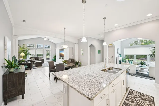 a large kitchen with kitchen island a chandelier and living room view