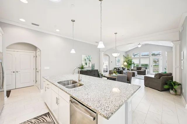 a large kitchen with kitchen island a stove a sink a counter space and a chandelier