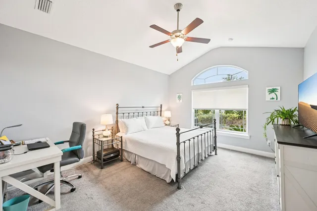 a bedroom with a bed a chandelier and a mirror on the dresser