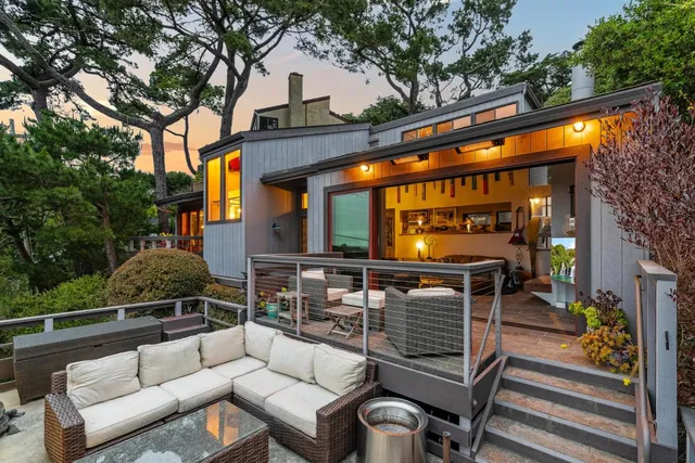 a view of a patio with couches table and chairs with wooden floor and fence