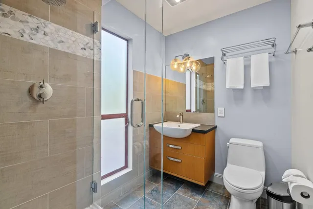 a bathroom with a toilet a sink a mirror a vanity and window